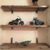 Scaffold board shelves fixed to the wall with solid steel brackets displaying motorcycles and a model aeroplane