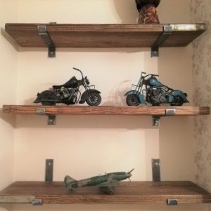 Scaffold board shelves fixed to the wall with solid steel brackets displaying motorcycles and a model aeroplane