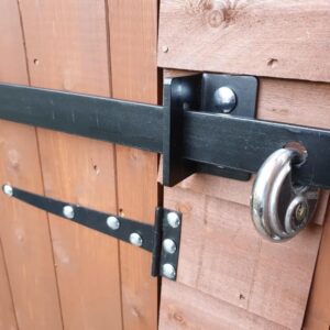 Close up photo of a black security bar padlocked on a garden shed.