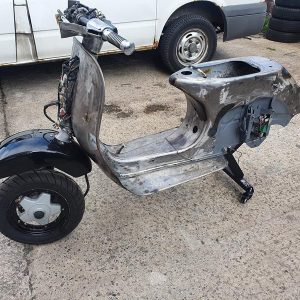 A dolly which fits to a scooter frame via the standard engine mount and the shock mount and allows you to move/store your engineless scooter with ease.  title