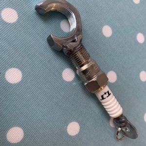 A bottle opener made out of a spark plug and a nut