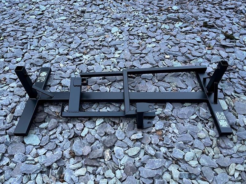 Lambretta engine test bed, powder coated in black, shown folded on some gravel.