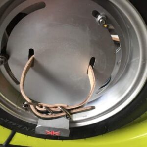 Closeup of spare wheel on a Lambretta Vega showing the strap used to fix a replica oil can to the spare wheel.