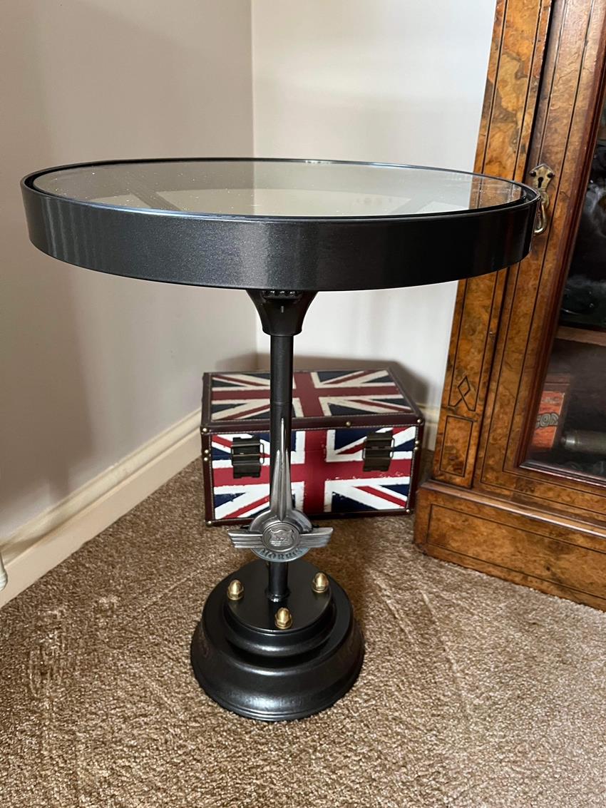 Side view of a Morris Minor coffee table made from a genuine steering wheel with base which includes an original badge.