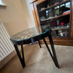 Side view of a glass fabricated table with an assortment of spanners inset within it and black powder coated legs