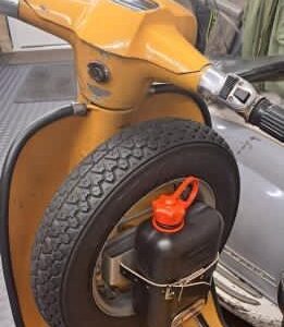 Small petrol can fixed to a spare wheel on a mustard colour Lambretta scooter