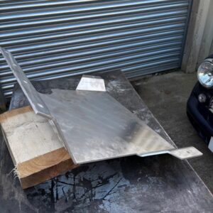 A classic mini sump guard on a piece of wood outside a workshop