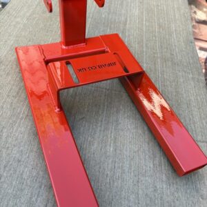 Close-up of part of a red metal engine stand for Honda C50, C70 and C90 motorbikes.