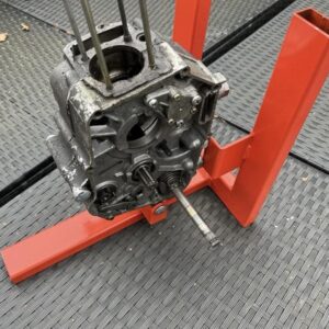 Red metal engine stand for Honda C50, C70 and C90 motorbikes, shown with an engine sitting on it.