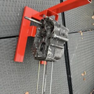 Red metal engine stand for Honda C50, C70 and C90 motorbikes, shown with an engine sitting on it.