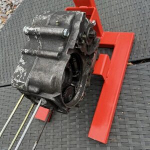 Red metal engine stand for Honda C50, C70 and C90 motorbikes, shown with an engine sitting on it.